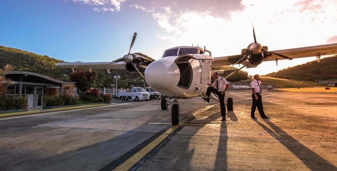 Avion à hélices et ses deux pilotes sur le tarmac de l’aéroport de Saint-Jean à Saint-Barthélemy au coucher du soleil